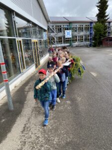 Kinder tragen einen Maibaum.